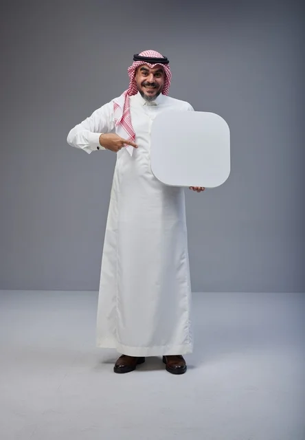 رجل سعودي يحمل لوحة بيضاء فارغة في الاستوديو