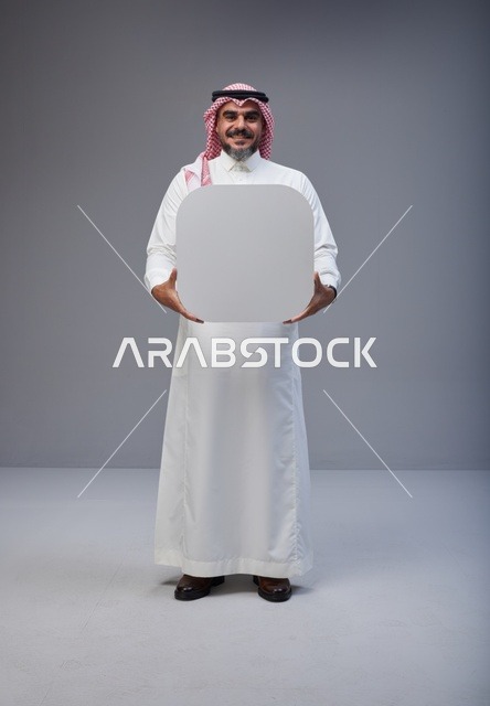 رجل سعودي في الاستوديو يحمل لوحة بيضاء فارغة