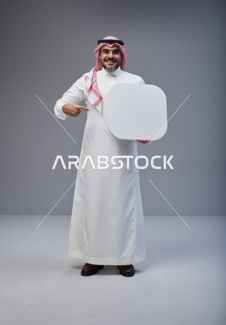 رجل سعودي يحمل لوحة بيضاء فارغة في الاستوديو