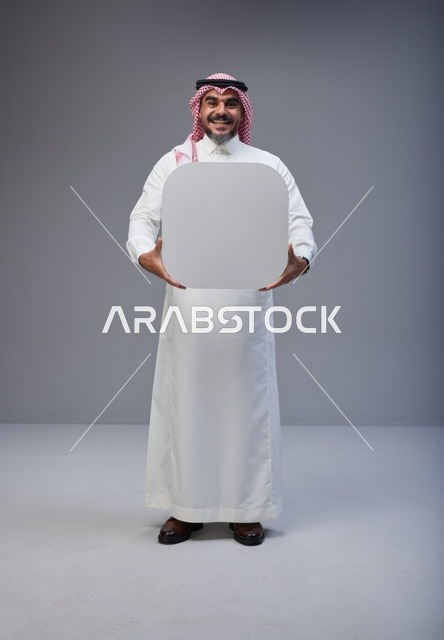 رجل سعودي يحمل لوحة بيضاء فارغة في الاستوديو