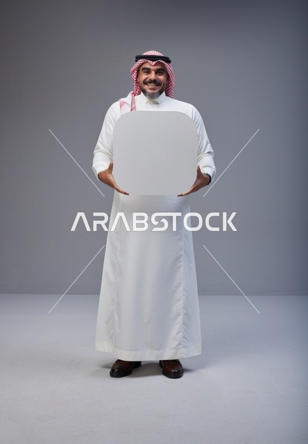 رجل سعودي يحمل لوحة بيضاء فارغة في الاستوديو