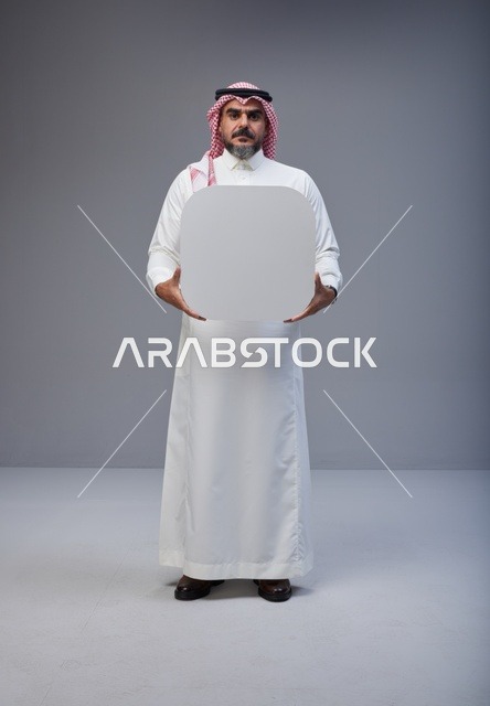 رجل سعودي يحمل لوحة بيضاء فارغة في الاستوديو