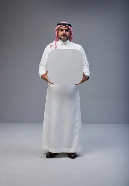 رجل سعودي يحمل لوحة بيضاء فارغة في الاستوديو