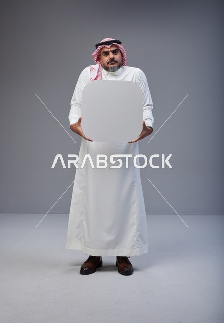 رجل سعودي يحمل لوحة بيضاء فارغة في الاستوديو