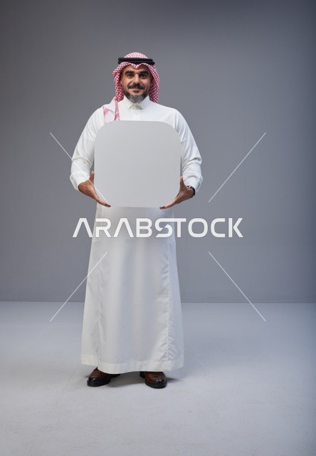 رجل سعودي يحمل لوحة بيضاء فارغة في استوديو