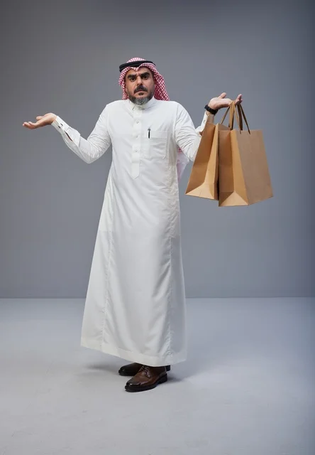 رجل سعودي بالزي التقليدي يحمل أكياس تسوق في استوديو رجل سعودي بالزي التقليدي يحمل أكياس تسوق في استوديو