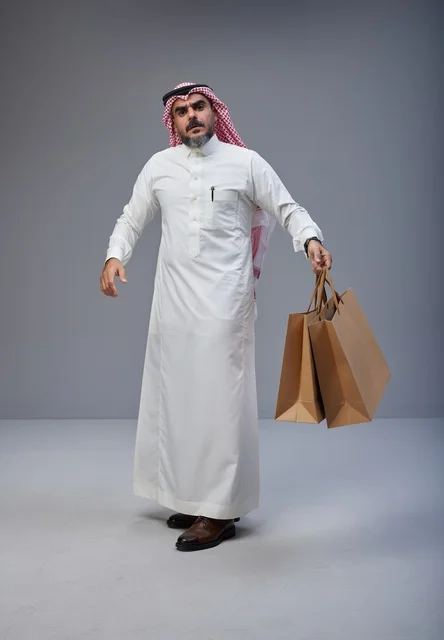 رجل سعودي بالزي التقليدي مع أكياس تسوق رجل سعودي بالزي التقليدي مع أكياس تسوق
