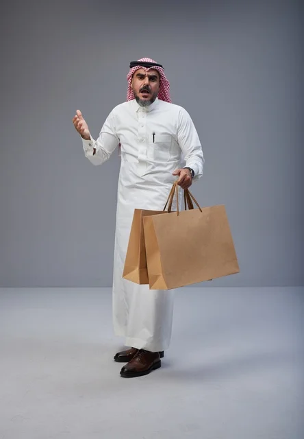 رجل سعودي غاضب يحمل أكياس تسوق ورقية في الاستوديو