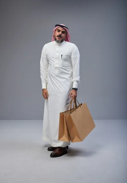 رجل سعودي يحمل أكياس تسوق بملامح تعب وإرهاق رجل سعودي يحمل أكياس تسوق بملامح تعب وإرهاق