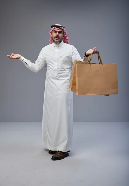 رجل سعودي بالزي التقليدي يحمل أكياس تسوق رجل سعودي بالزي التقليدي يحمل أكياس تسوق