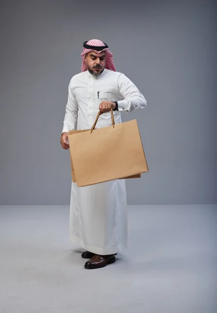 رجل سعودي بالزي التقليدي يحمل أكياس تسوق