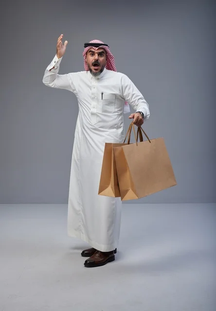 رجل سعودي يحمل أكياس تسوق بتعبير وجه مندهش