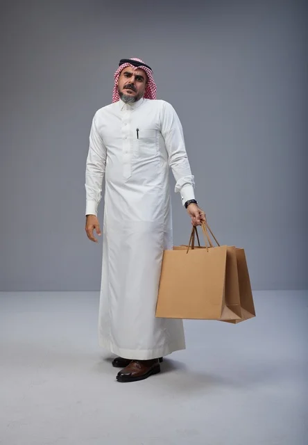 Saudi Man in Traditional Thobe Holding Shopping Bags