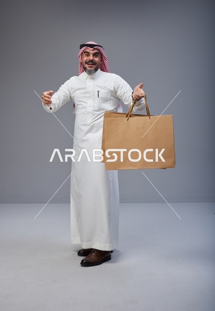 رجل سعودي يحمل أكياس تسوق ورقية في الاستوديو