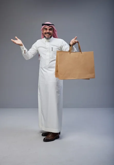 Saudi Man Holding Shopping Bags in Traditional Dress