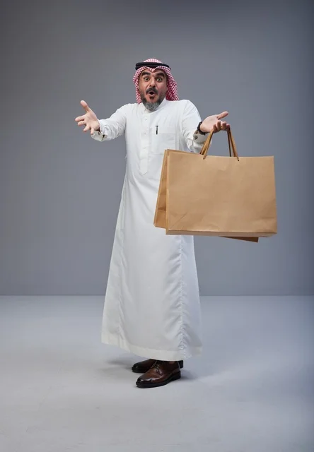 Surprised Saudi Man Holding Paper Shopping Bags in Studio