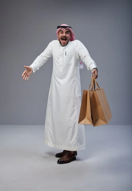 رجل سعودي متحمس يحمل أكياس تسوق في الاستوديو