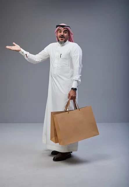 رجل سعودي بالزي التقليدي يحمل أكياس تسوق