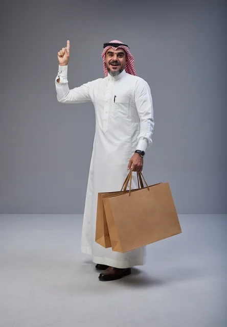 رجل سعودي يحمل أكياس تسوق ويشير للأعلى رجل سعودي يحمل أكياس تسوق ويشير للأعلى