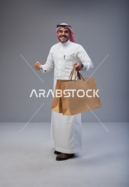 رجل سعودي يحمل أكياس تسوق ورقية في الاستوديو
