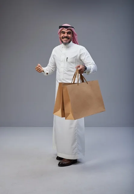 رجل سعودي يحمل أكياس تسوق ورقية في الاستوديو