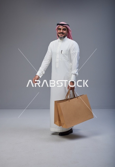Saudi Man in Traditional Thobe Holding Shopping Bags