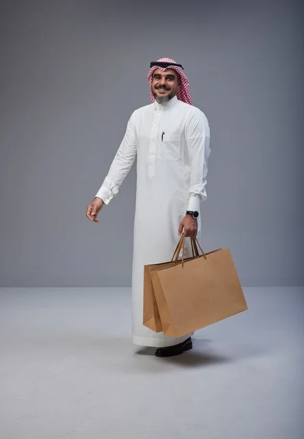 Saudi Man in Traditional Thobe Holding Shopping Bags