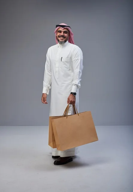 Saudi man in traditional attire holding shopping bags