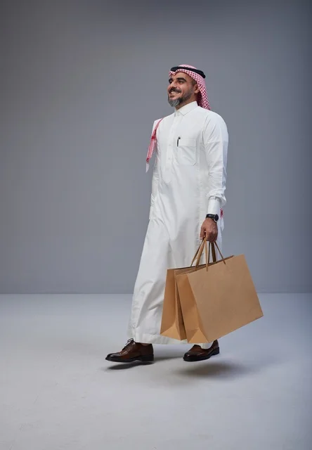 رجل سعودي يحمل أكياس تسوق في الاستوديو