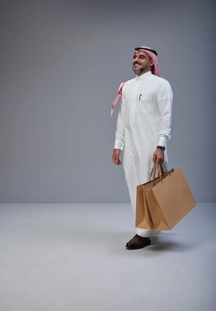 رجل سعودي يحمل أكياس تسوق في استوديو تصوير