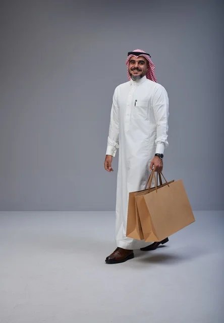 Saudi Man in Traditional Thobe Holding Shopping Bags
