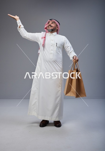 رجل سعودي بالزي التقليدي يحمل أكياس تسوق