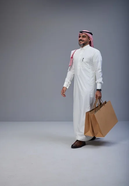 رجل سعودي بالزي التقليدي يحمل أكياس تسوق