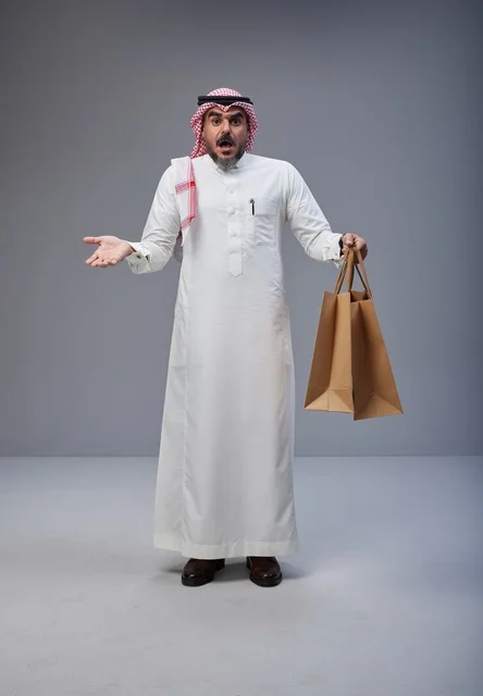 رجل سعودي مندهش يحمل أكياس تسوق في الاستوديو