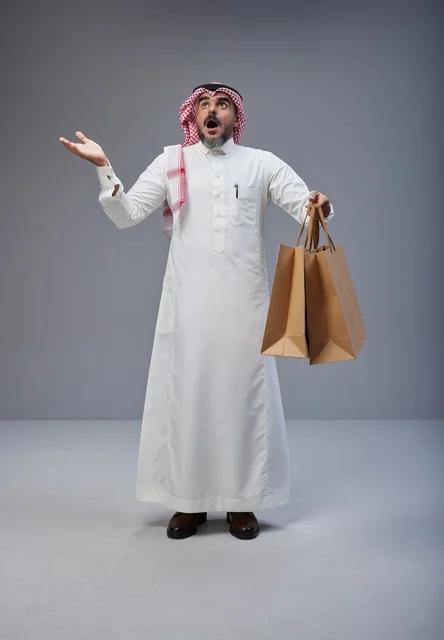 رجل سعودي يحمل أكياس تسوق بتعبير مندهش