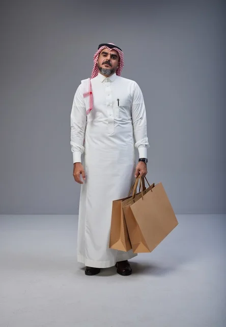 رجل سعودي بالزي التقليدي يحمل أكياس تسوق