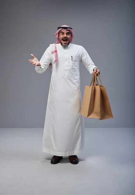 رجل سعودي متحمس يحمل أكياس تسوق في الاستوديو