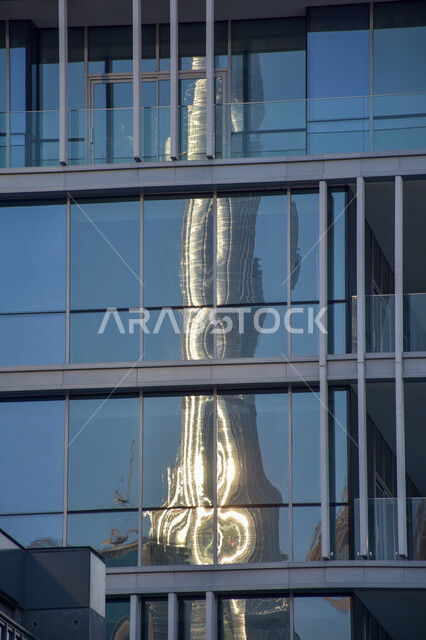 A reflection of the Burj Khalifa in the glass of a skyscraper in Dubai, the famous landmarks of the Emirates, towers and skyscrapers, tourism in the United Arab Emirates.
