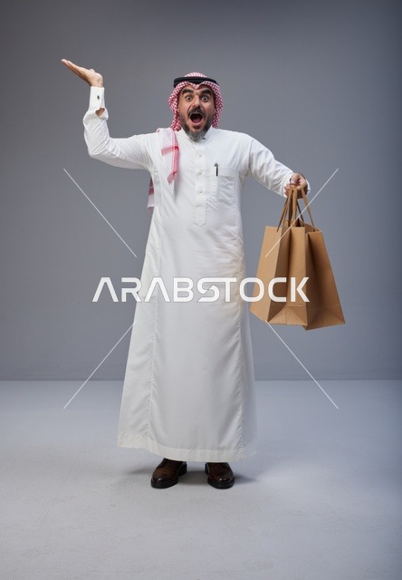 Surprised Saudi Man Holding Shopping Bags in Studio
