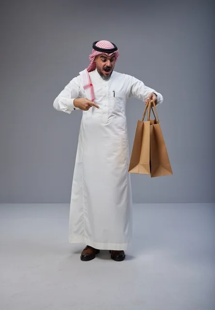 رجل سعودي مندهش يحمل أكياس تسوق ورقية