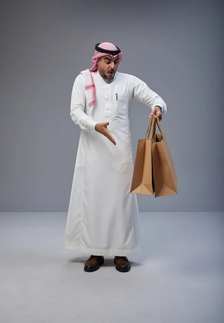 رجل سعودي يحمل أكياس تسوق بتعبير مندهش