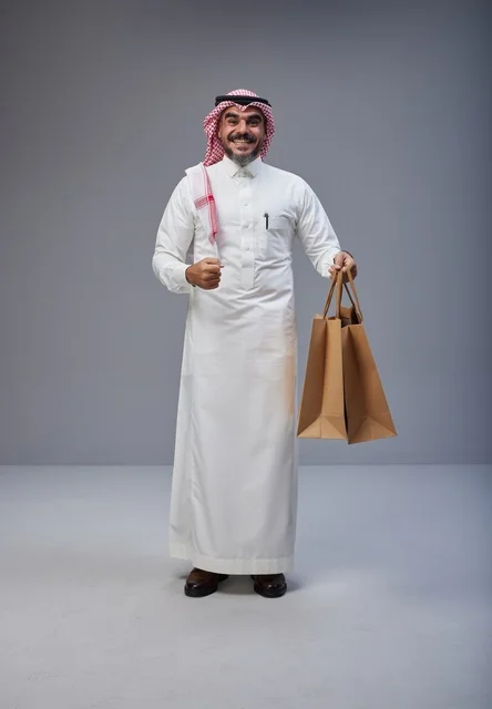 رجل سعودي بالزي التقليدي يحمل أكياس تسوق في استوديو