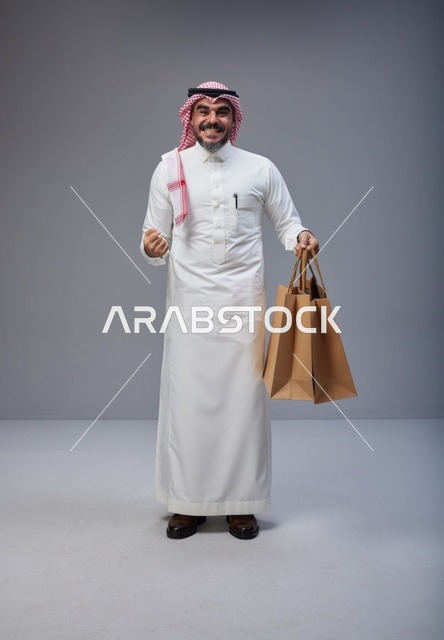 Smiling Saudi Man Holding Paper Shopping Bags in Studio