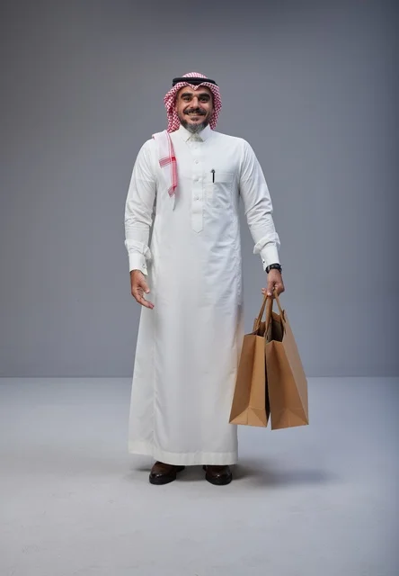 Saudi man in traditional attire holding shopping bags