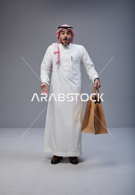 Surprised Saudi Man Holding Paper Shopping Bags in Studio