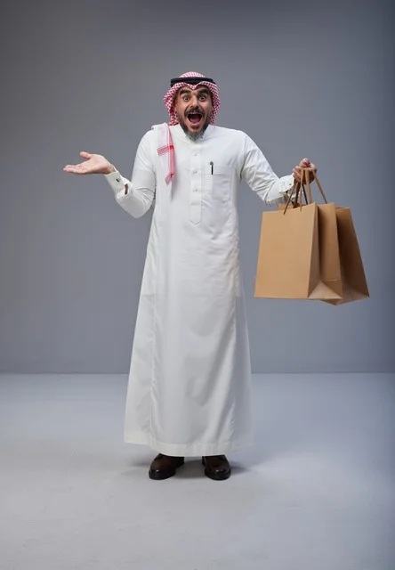 رجل سعودي مندهش يحمل أكياس تسوق في الاستوديو