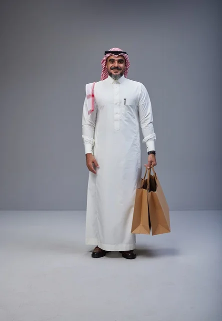 رجل سعودي يحمل أكياس تسوق في تصوير استوديو