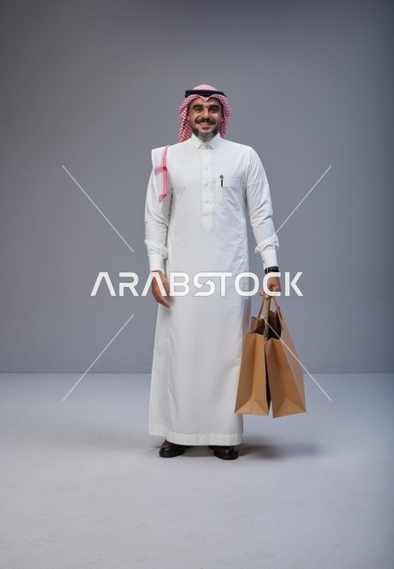 رجل سعودي بالزي التقليدي يحمل أكياس تسوق