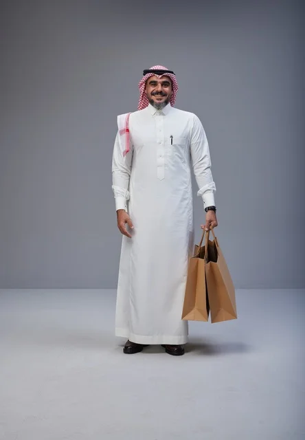 Saudi man in traditional attire holding shopping bags