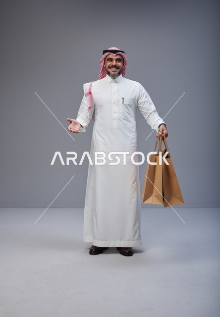 رجل سعودي بالزي التقليدي يحمل أكياس تسوق